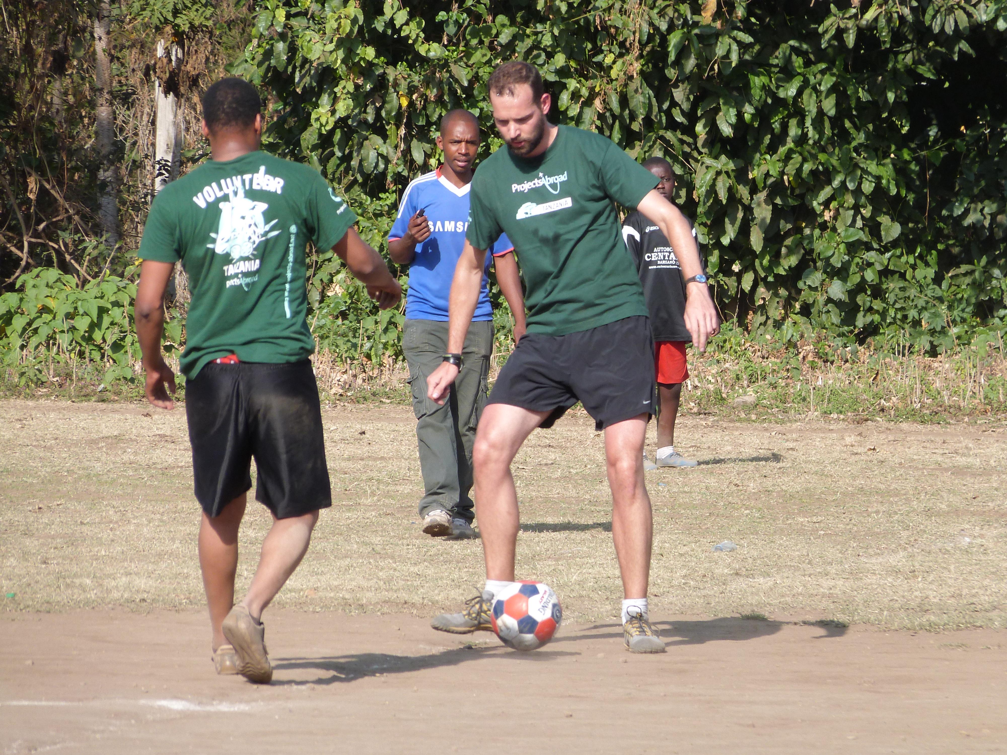 Two Projects Abroad volunteers pass a football while coaching sports in schools in Tanzania Volunteers practise their passing in preparation to coach sports in schools in Tanzania